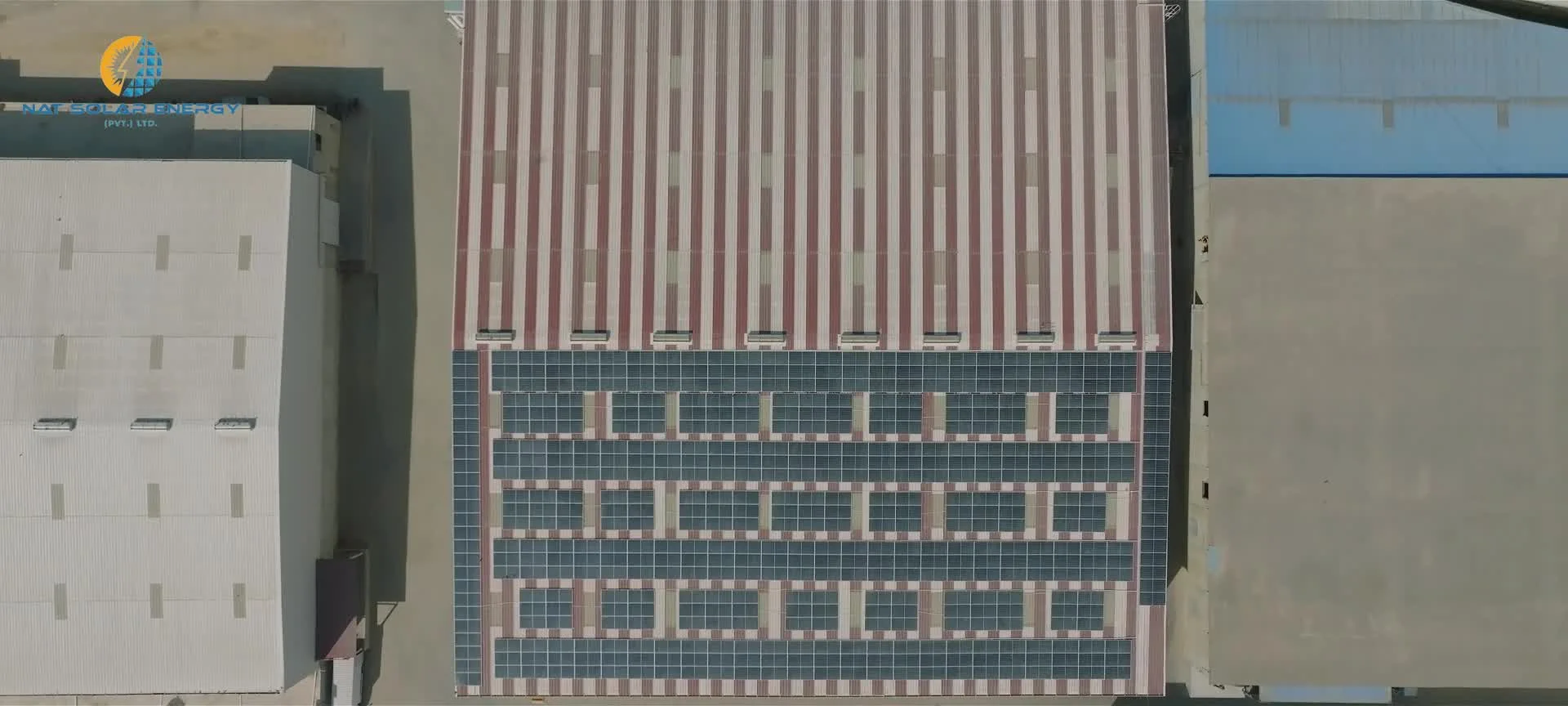 Aerial photograph of solar panels on a striped industrial roof